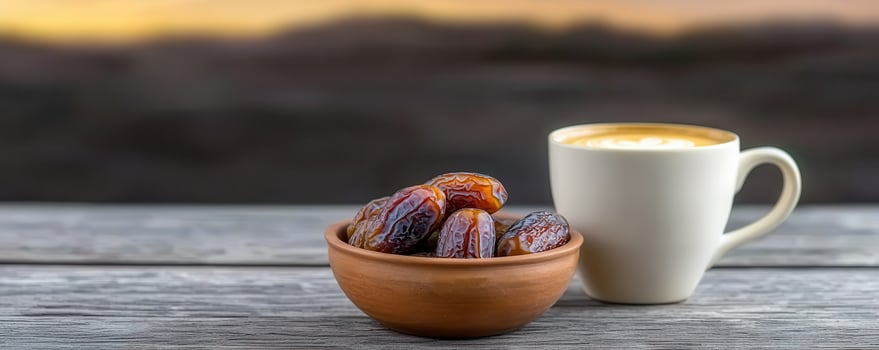 Dried dates in clay bowl with cup of coffee on wooden table at sunset photo
