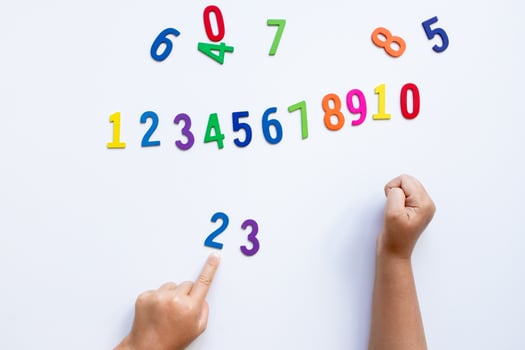Child learning numbers with colorful wooden numerals on white background photo