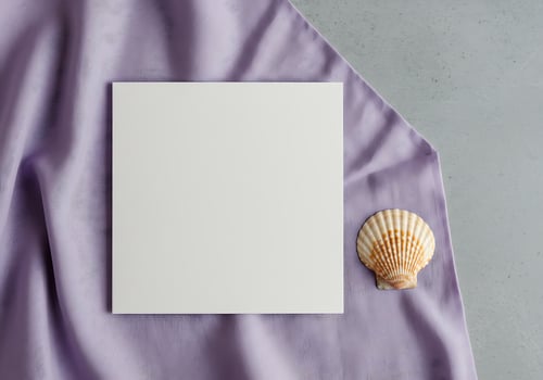 A white sheet of paper and seashell on a purple cloth photo