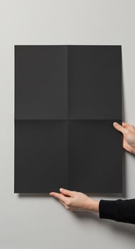 A person holding a black square piece of paper photo