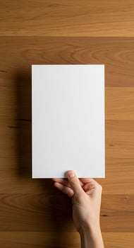A person holding a blank piece of paper on a wooden table photo