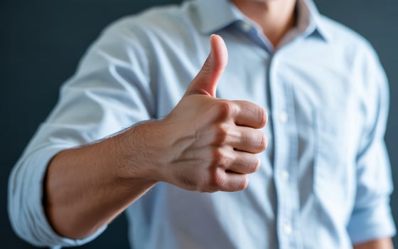 Man in light blue shirt gives thumbs up gesture of approval photo