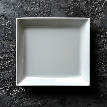 Empty White Square Plate on a Dark Textured Background Surface photo