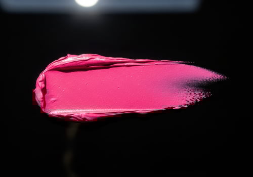 Pink lipstick swatch with shimmer on black background photo
