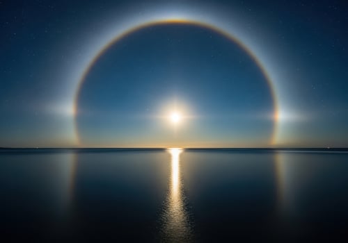Moon halo phenomenon over the ocean at night with stars photo