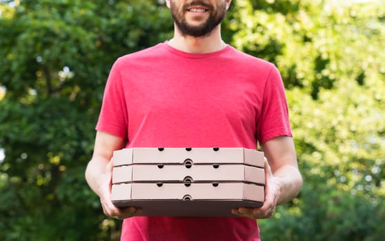 Smiling pizza delivery man holds pizza boxes outdoor. Mockup. Delivery service. Online order. Selective focus. photo
