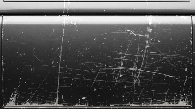 A black and white photo of a scratched and dirty window