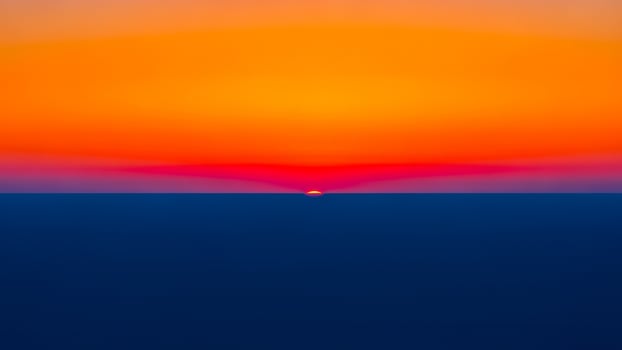 A sunset over the ocean with a bright orange sky photo