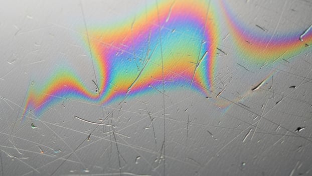 A rainbow colored streak on a metal surface photo