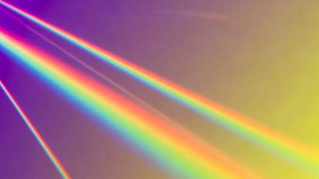 A rainbow light beam is shining through a dark background photo