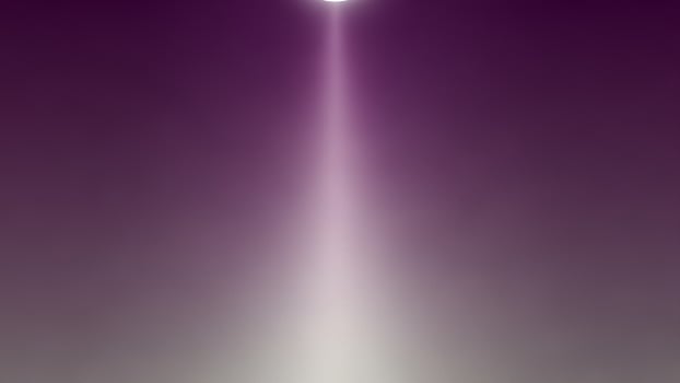 A purple light beam is shining through the sky photo