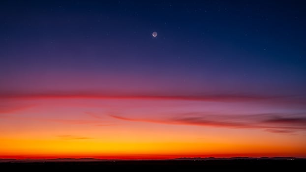 The moon and a crescent are seen in the sky at sunset photo