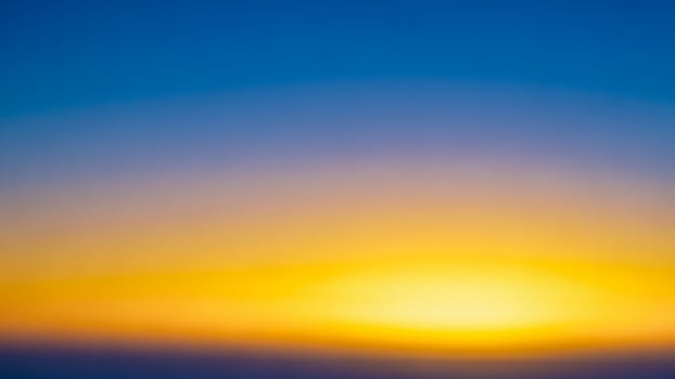 A blurry image of the sun setting over a blue and yellow background photo