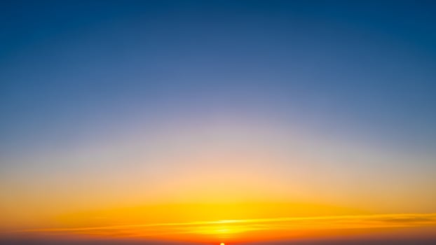 The sun sets over the ocean in a blue sky photo