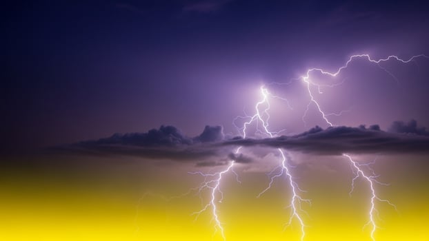 Lightning strike over the clouds with yellow and blue sky photo