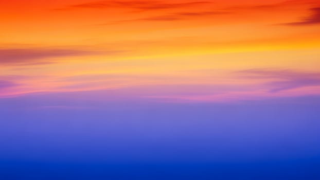A colorful sunset over the ocean with a plane flying in the sky photo