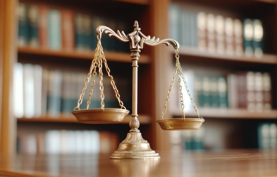 Antique scale of justice bronze balance on wood surface with bookshelves photo