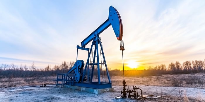 Oil pumpjack extracting resources during sunrise in open field photo