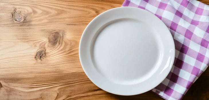 White plate on wooden table with checkered napkin for food presentation and dining photo