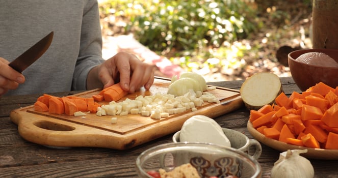 Fresh cut carrot preparation outdoors with various vegetables on wooden cutting board, meal prep in natural setting with vibrant colors and rustic charm photo