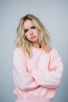 Sad young woman with arms crossed in studio portrait expressing unhappy emotion photo