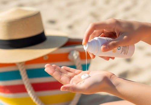 Hands applying sunscreen on beach with straw hat lotion photo
