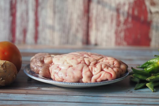 A animal brain placed on a silver plate next to assorted vegetables photo
