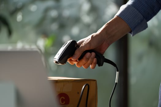 Focused small business owner using a handheld barcode scanner to process packages in a startup workspace for e-business photo