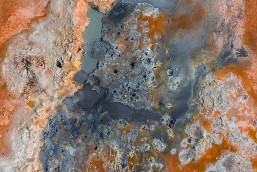 Geothermal landscape in Iceland featuring bubbling mud pots, steaming vents, mineral deposits, and scattered milky water pools in vibrant hues. photo