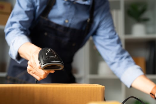 Small business owner scanning packages with a barcode scanner in a startup workspace for efficient e-business operations photo