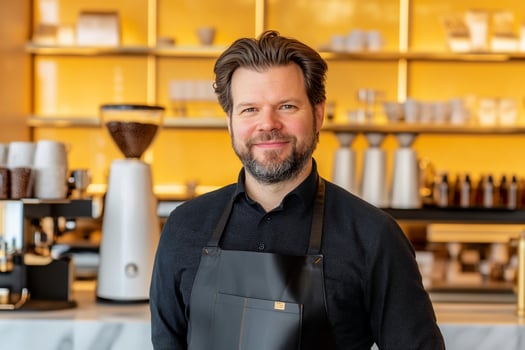 Professional barista smiling inside coffee shop serving customers with friendly hospitality photo