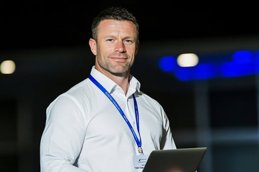 Professional man holding laptop at corporate event or office setting indoors photo