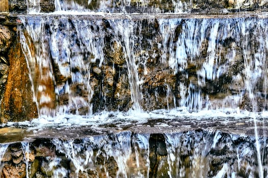 Mineral natural water flows over stepped mountain stones photo