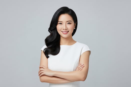 Elegant Asian Woman with Black Hair and White Dress, Arms Crossed photo