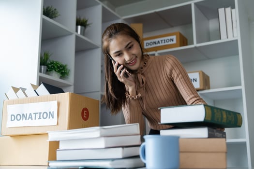 Young Woman Organizing Donation Boxes with Books and Supplies in a Modern Office Setting photo