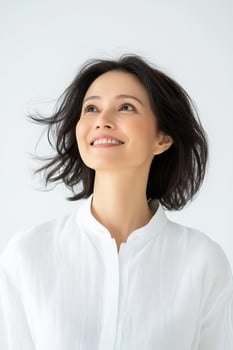 Smiling asian woman looking upwards with hope and optimism in clean white background photo