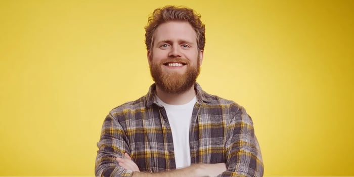 Smiling man with beard posing confidently against yellow background in casual clothing photo