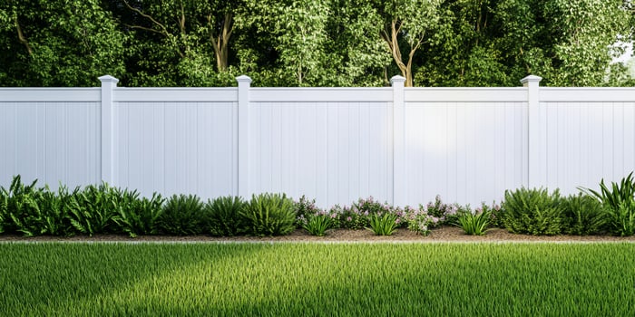 White fence bordering green lawn and foliage in residential landscape photo