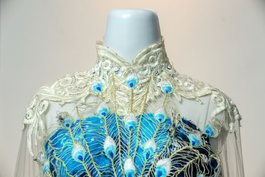 Close-up of a luxurious blue gown with detailed peacock embroidery and lace neckline, blending elegance and artistry, perfect for weddings, parties, and special formal occasions. photo