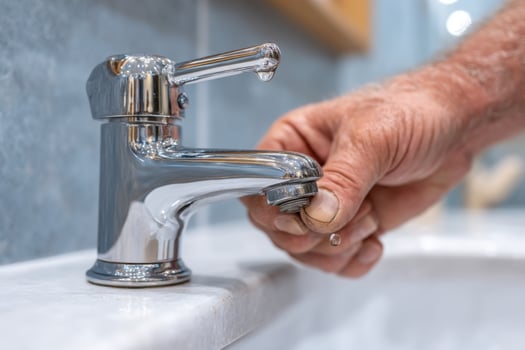 A man is fixing a faucet with a metal handle photo