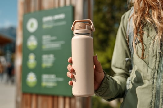 A woman holding a water bottle in front of a wooden sign photo