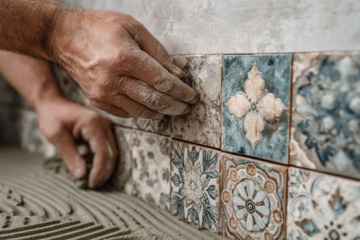 A man is laying tile on a wall photo