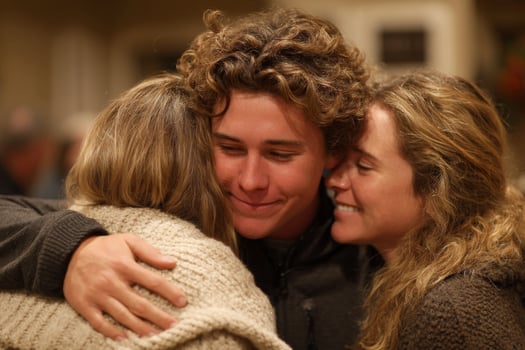 A young man hugs two women at a party photo