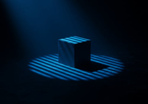 A blue cube in the dark with light coming from the top photo