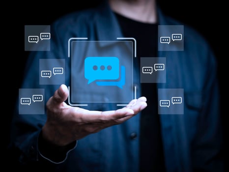 A person is holding a screen with a blue square that has a bunch of speech photo
