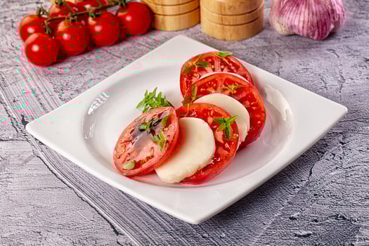 A white plate topped with sliced tomatoes and cheese photo