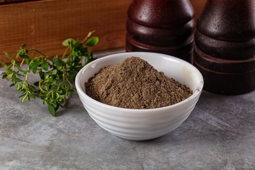 A bowl of brown powder next to a bottle of wine photo