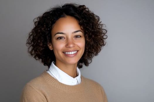Smiling woman portrait against gray background happy young adult with curly hair photo
