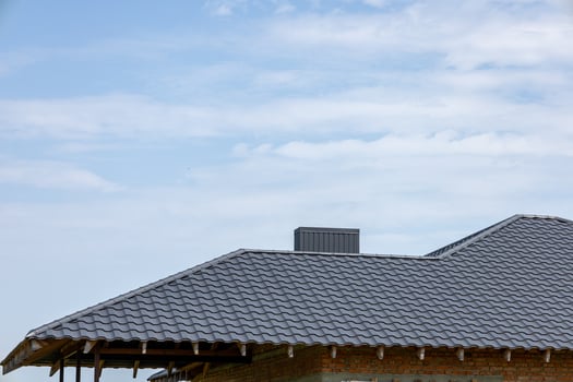 Construction of a new house showcases a gray tiled roof under a clear blue sky, reflecting progress in suburban development photo