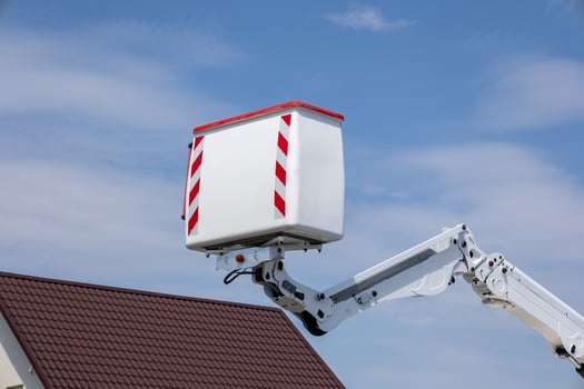 Aerial lift equipment is raised to the roof of a building during construction work, showcasing the machinery against a clear blue sky photo